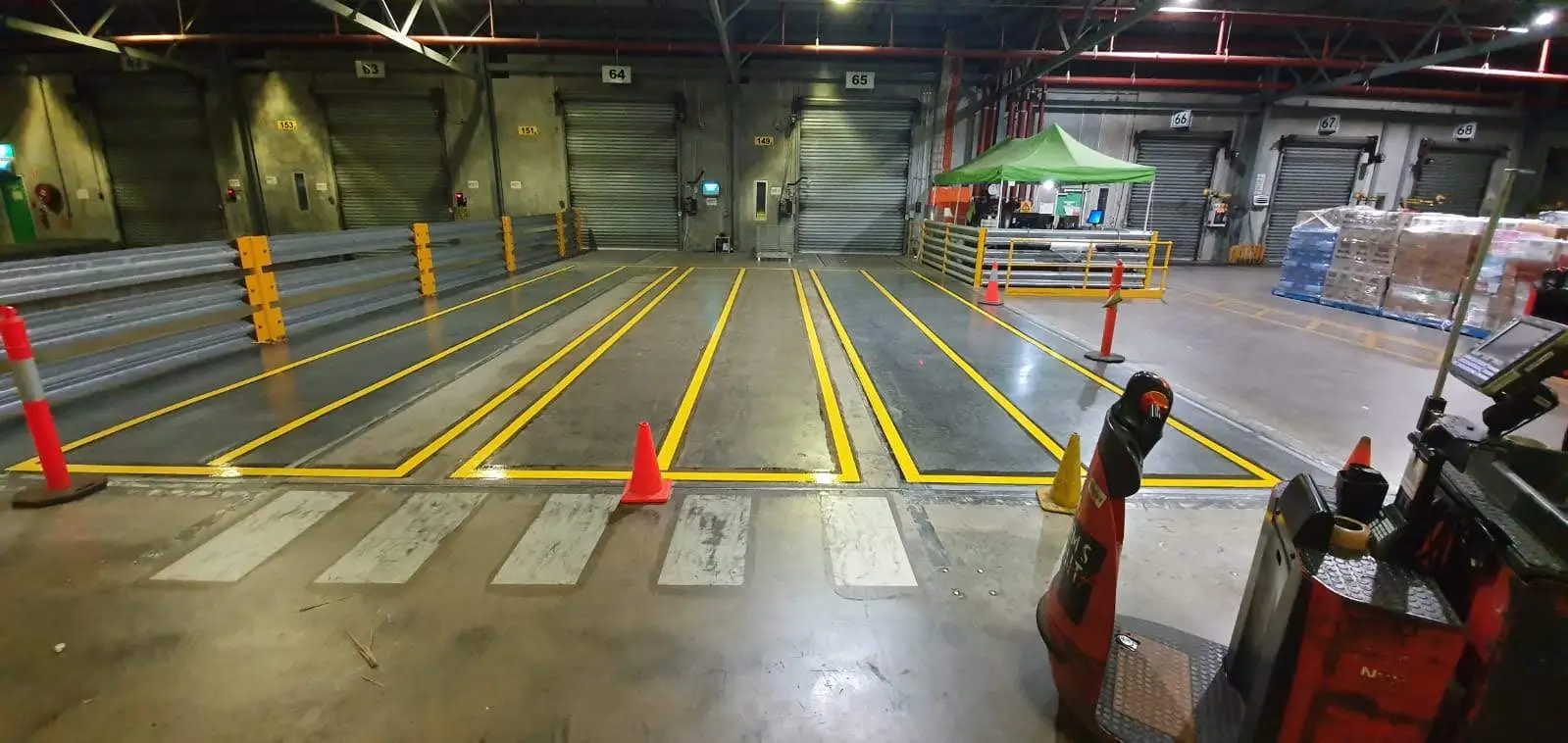 Freshly painted yellow forklift lane line marking inside a Brisbane warehouse